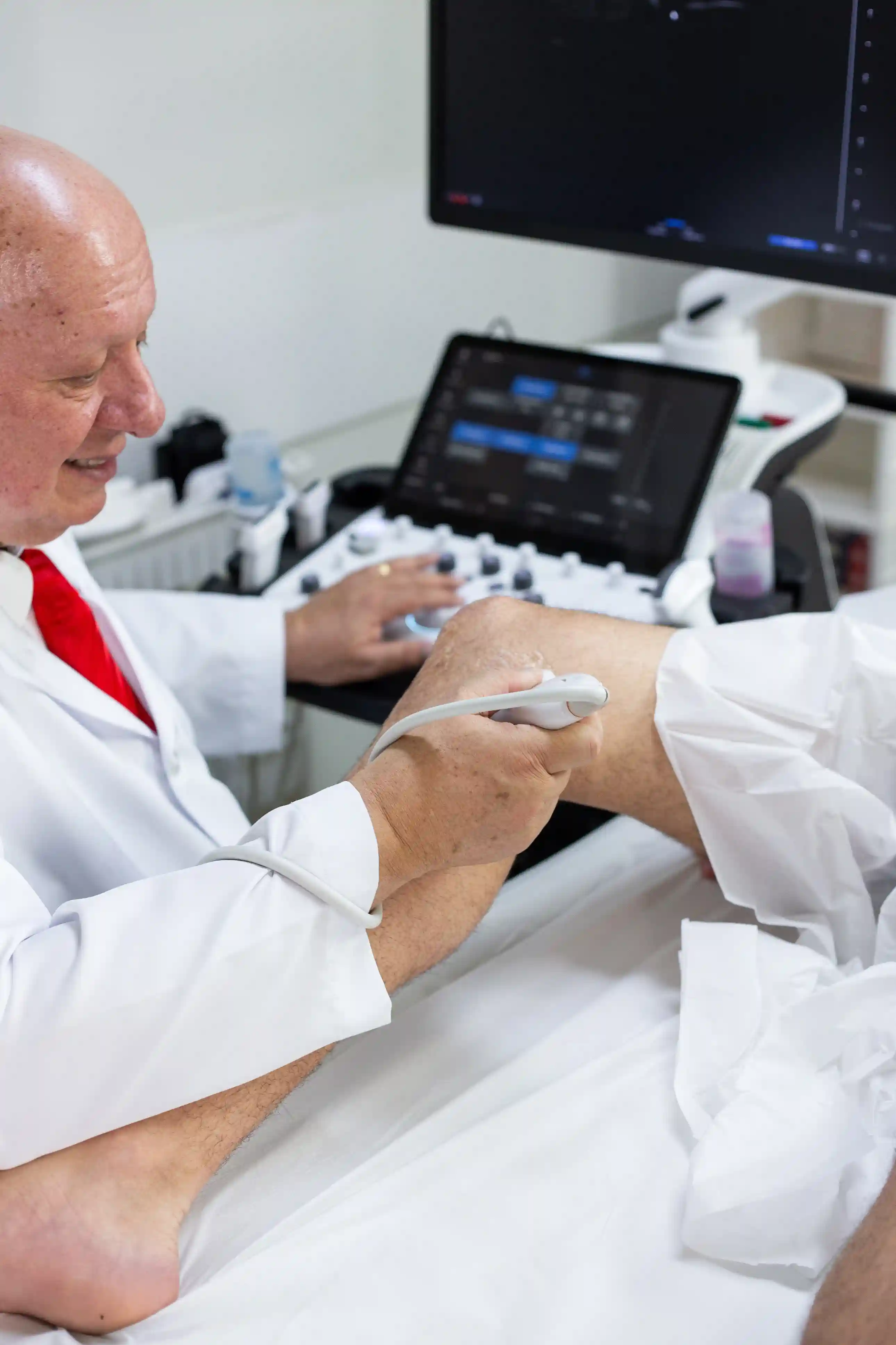 Dr. Monres Gomes realizando exame de ultrassonografia musculoesquelética no joelho de um paciente.