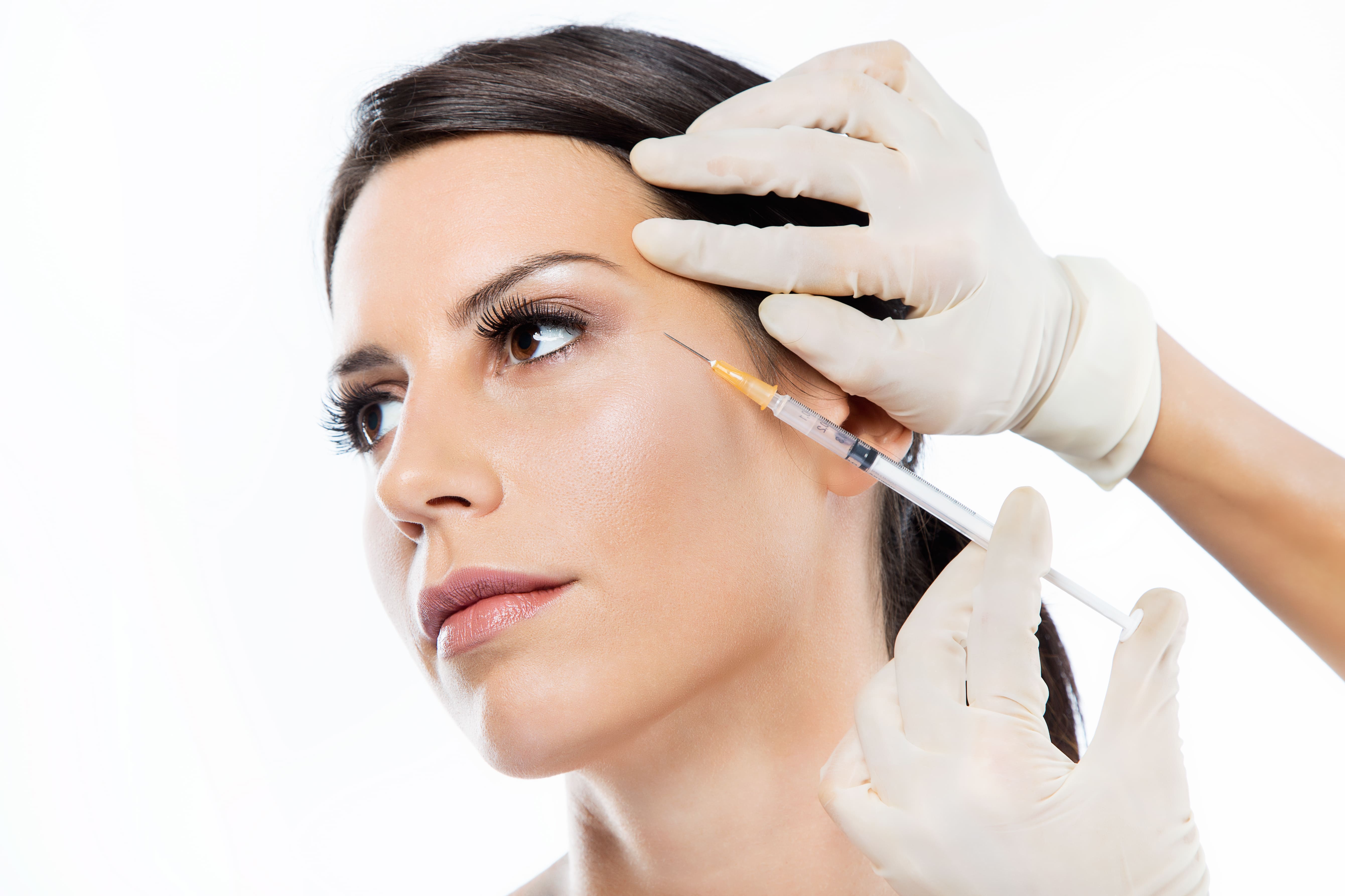 Médico aplicando toxina botulínica periorbital lateral (pés de galinha), com técnica intramuscular superficial direcionada ao músculo orbicular do olho, em ambiente ambulatorial.